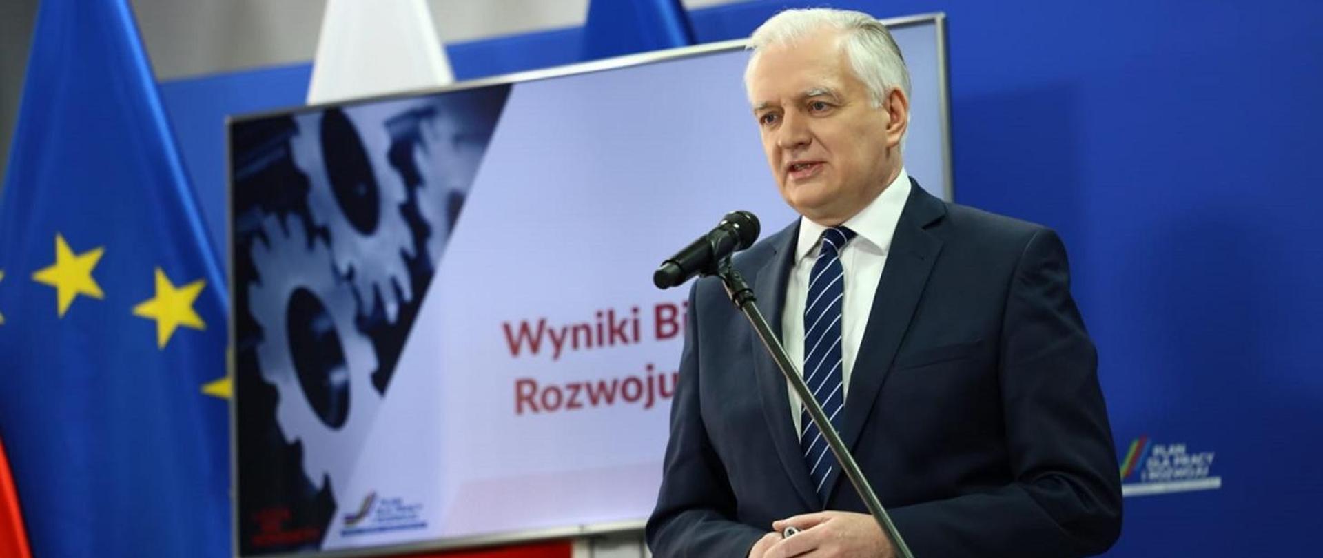 
Deputy Prime Minister, Minister of Economic Development, Labour and Technology, Jarosław Gowin, standing next to the lectern, behind him Polish and EU flags and the screen displaying inscription White Paper on Industrial Development
