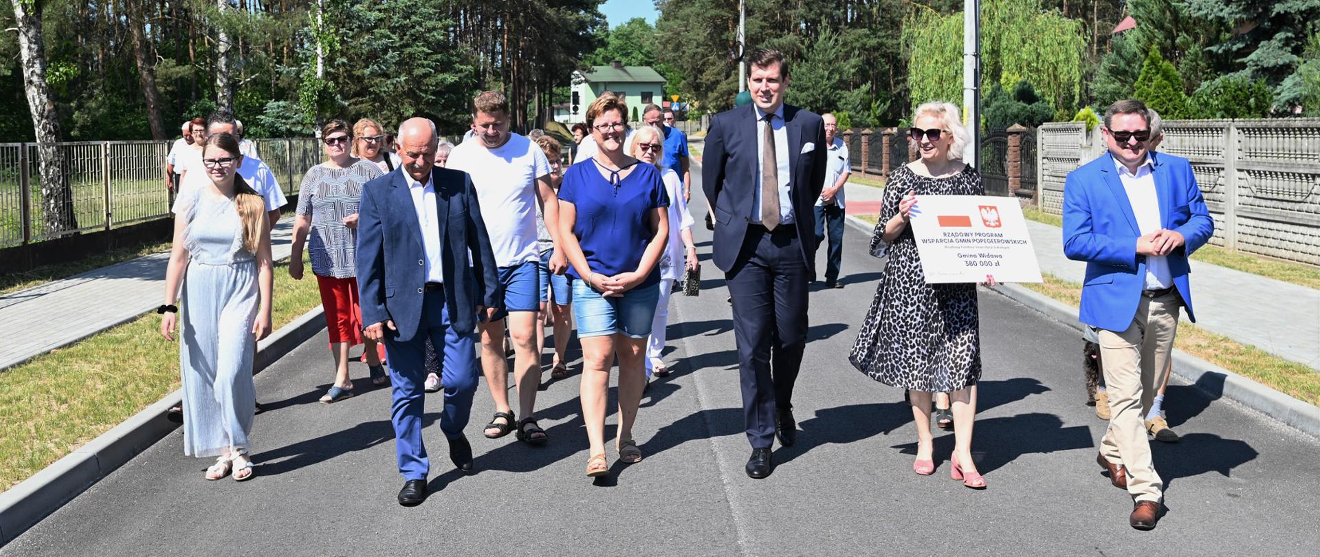 Wojewoda łódzki Tobiasz Bocheński wraz z mieszkańcami gminy Widawa spaceruje po nowo wyremontowanej drodze