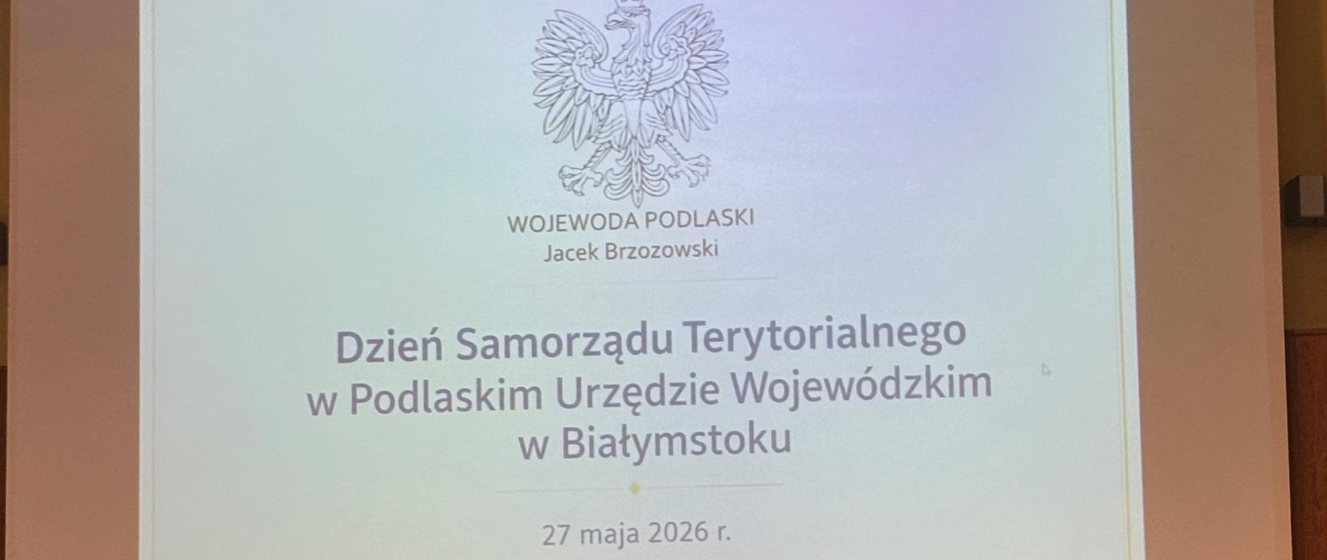 Prezentacja mężczyzny odbywa się przed flagami, podkreślając kontekst międzynarodowy wydarzenia. 
