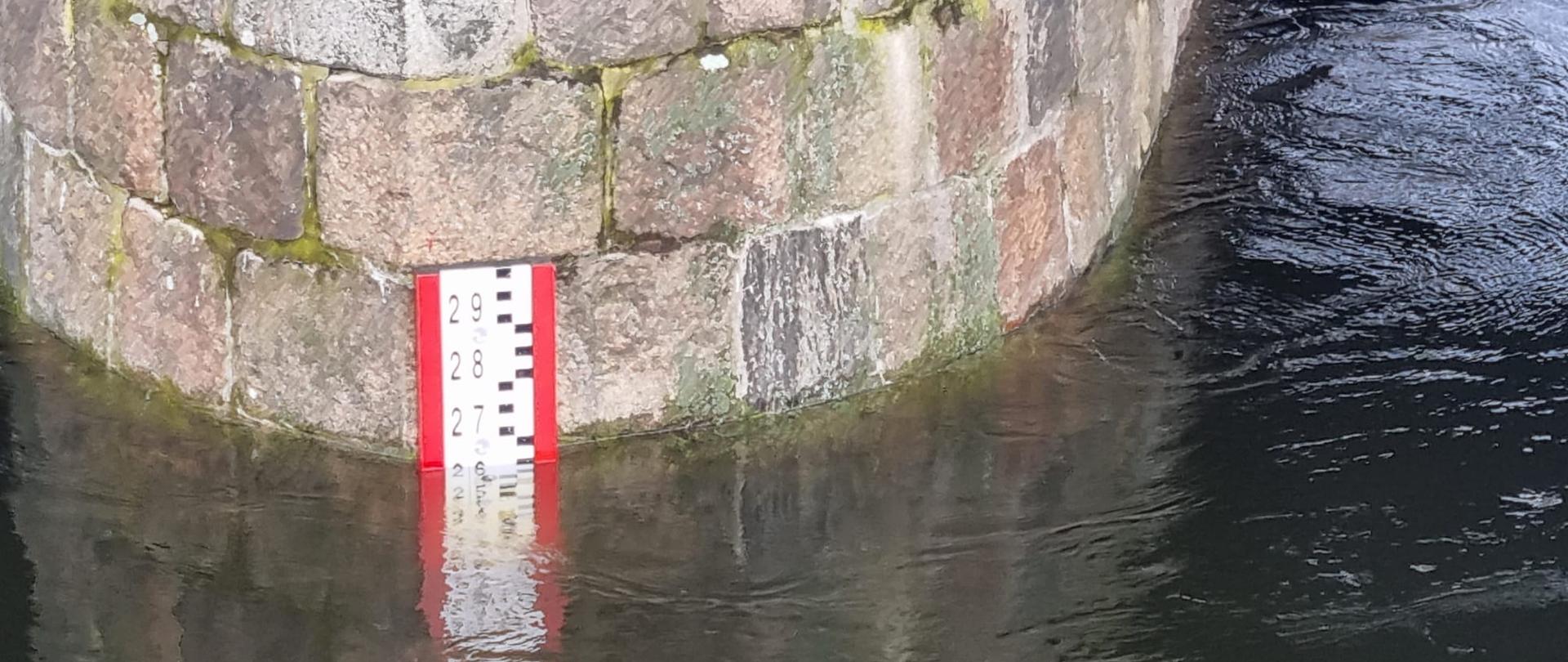 Zdjęcie przedstawia filar mostu na rzece Warta z umieszczonym wskaźnikiem stanu poziomu wody