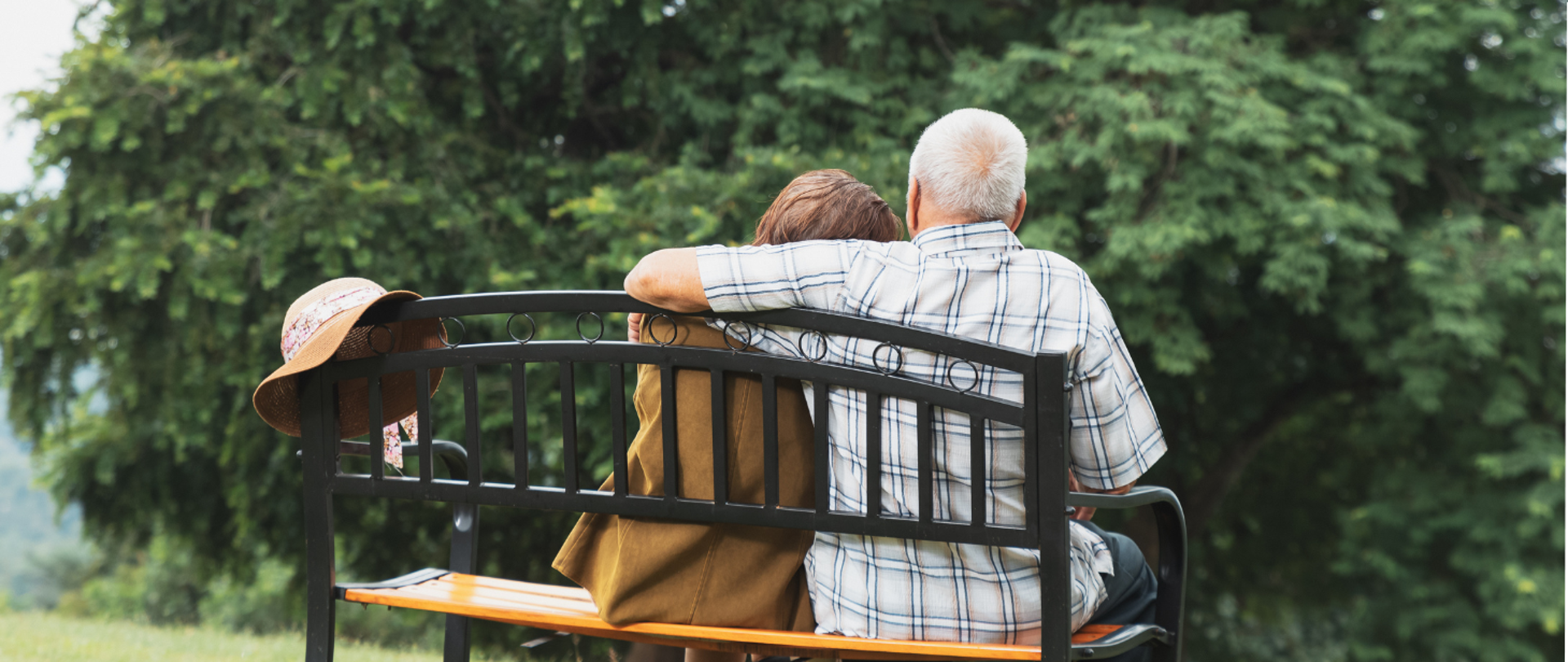 dwoje ludzi siedzi na ławce. mężczyzna obejmuje ramieniem kobietę