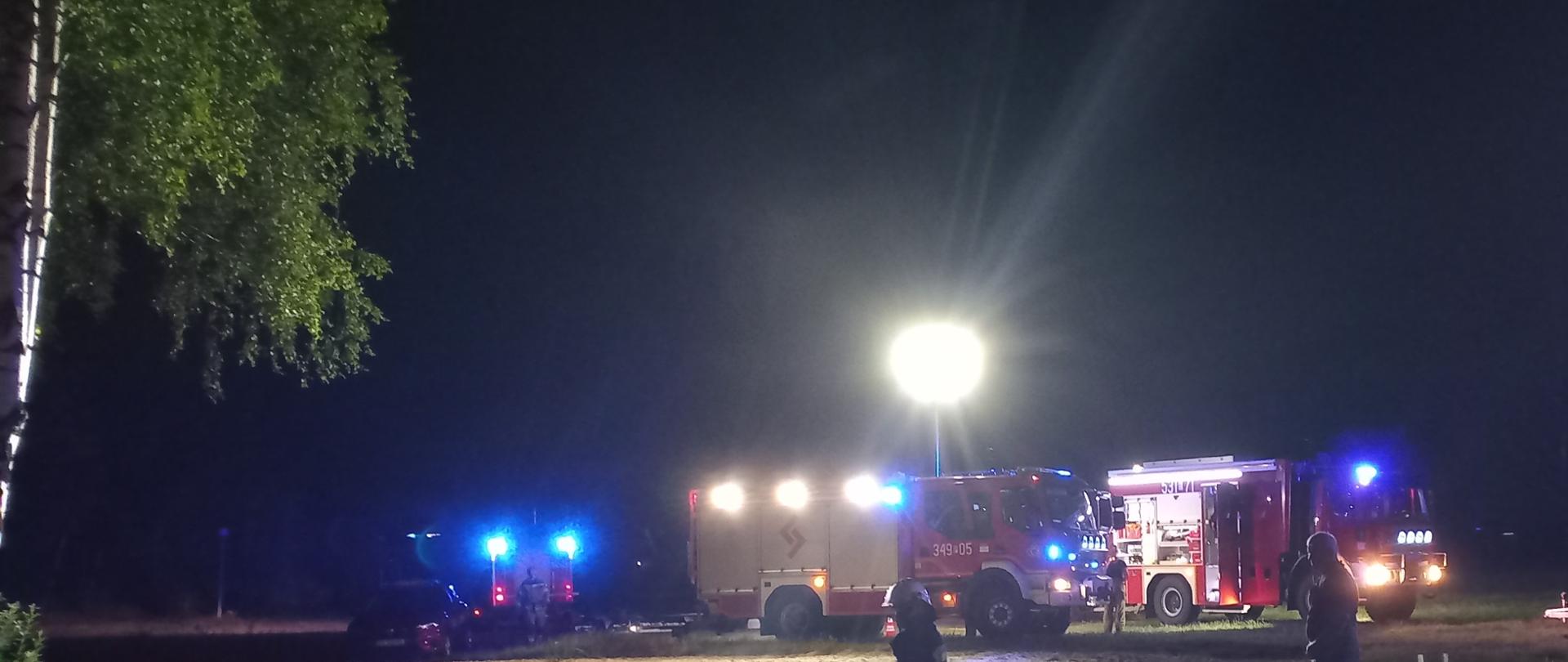 Pora nocna, samochody ratowniczo-gaśnicze, sztuczne światło, drzewa