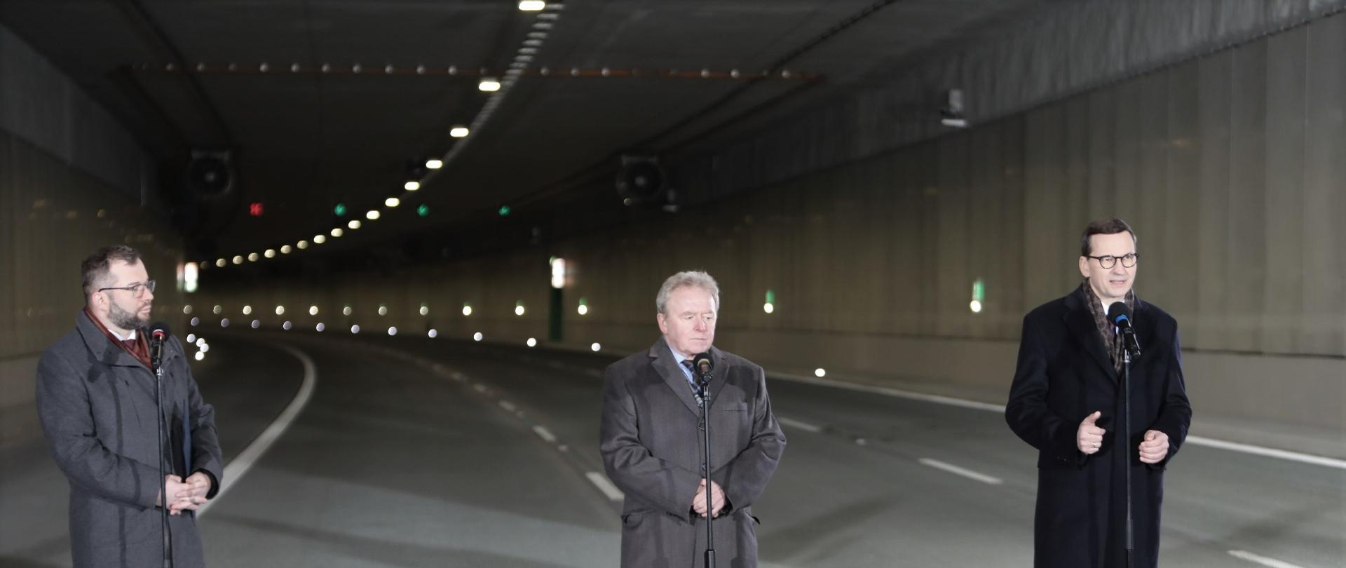Na tle tunelu stoją od lewej minister Grzegorz Puda, Komisarz UE ds. Rolnictwa Janusz Wojciechowski oraz premier Mateusz Morawiecki