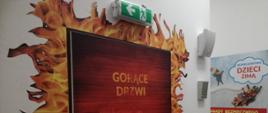 Zdjęcie przedstawia salę edukacyjna "Ognik" w Komendzie Powiatowej Państwowej Straży Pożarnej w Koluszkach. Na zdjęciu widoczne tzw. gorące drzwi. 
