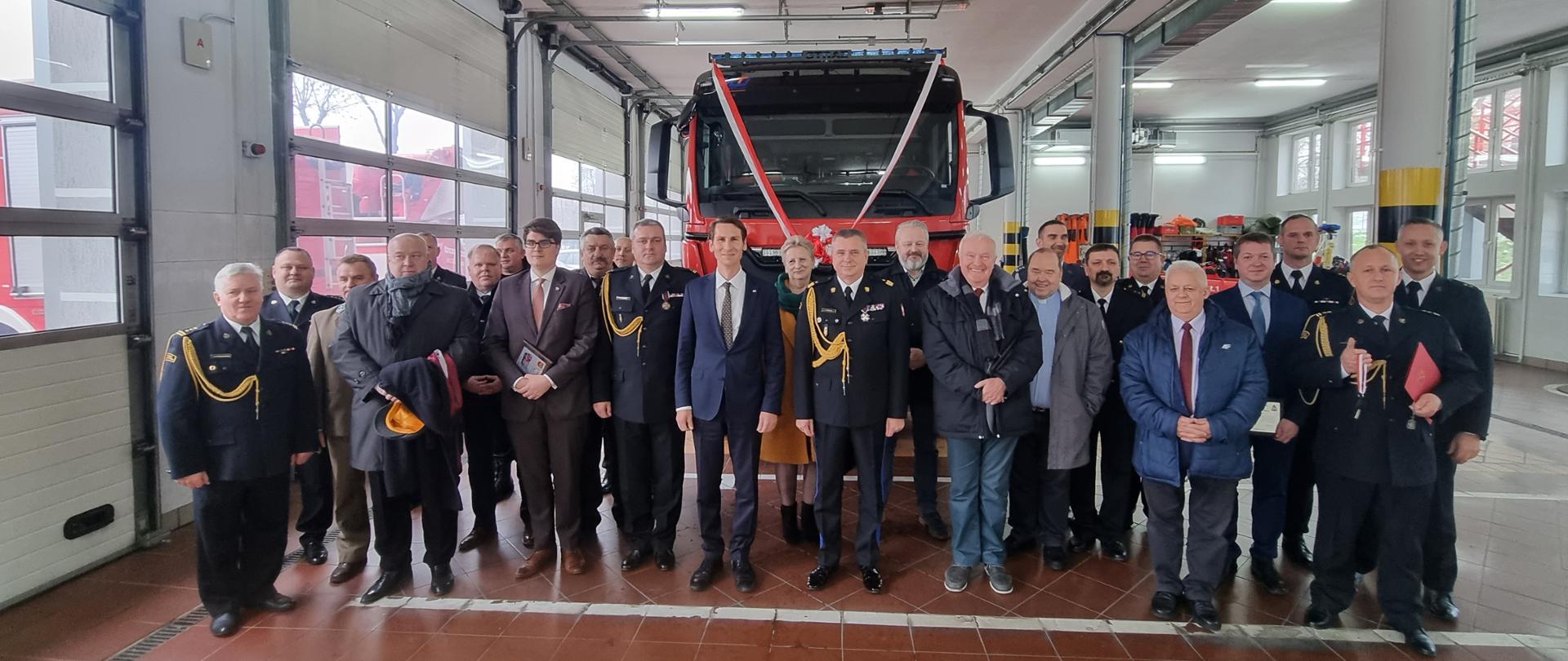 W garażu przed nowym pojazdem stoją zaproszeni goście i funkcjonariusze