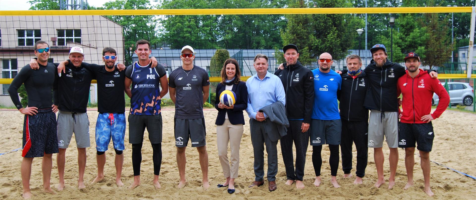 Minister Danuta Dmowska-Andrzejuk na wspólnym zdjęciu z kadrą Polski w siatkówce plażowej mężczyzn.
