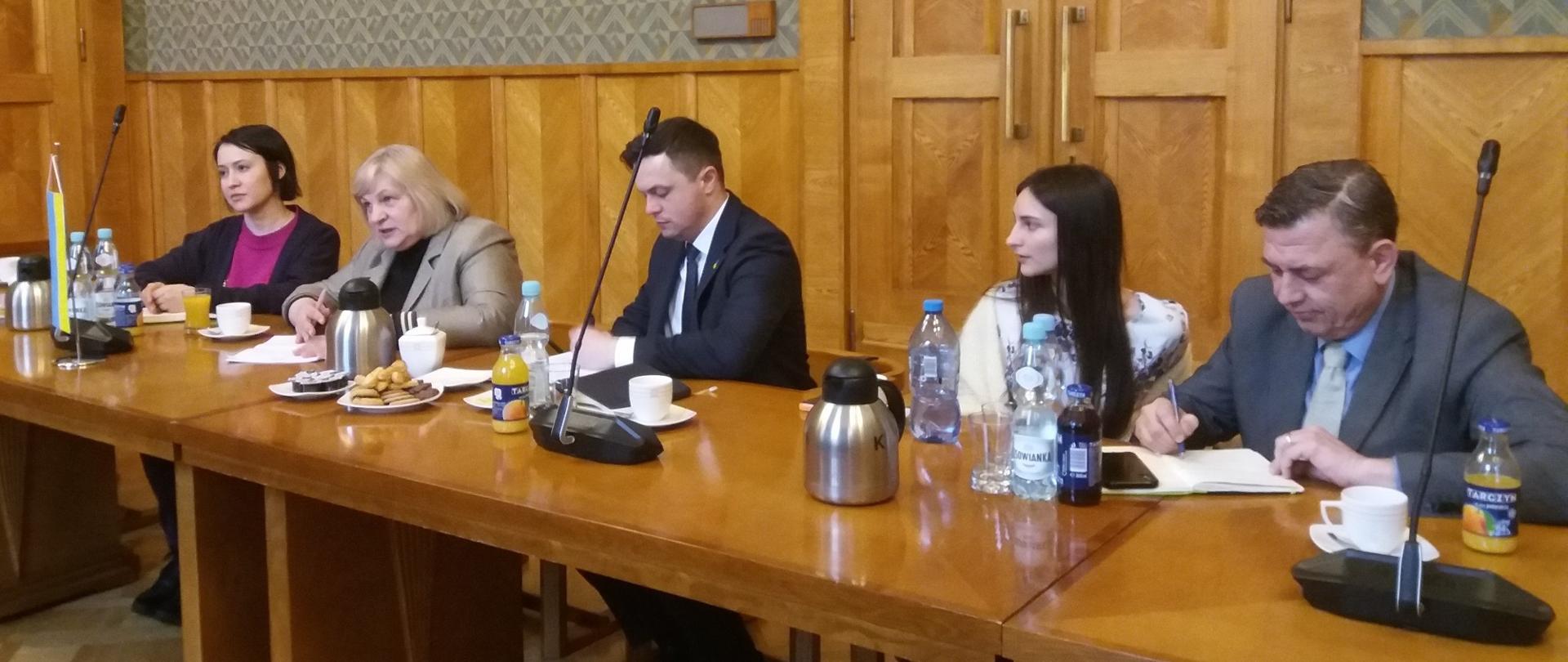 Uczestnicy spotkania siedzą i rozmawiają przy stole.