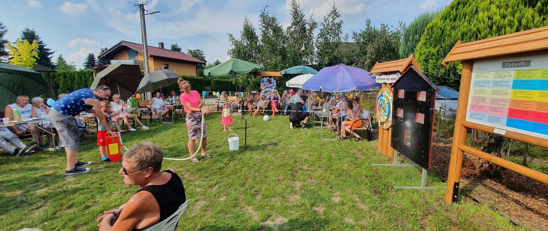 Dzieci polewają makietę domku z hydronetki.