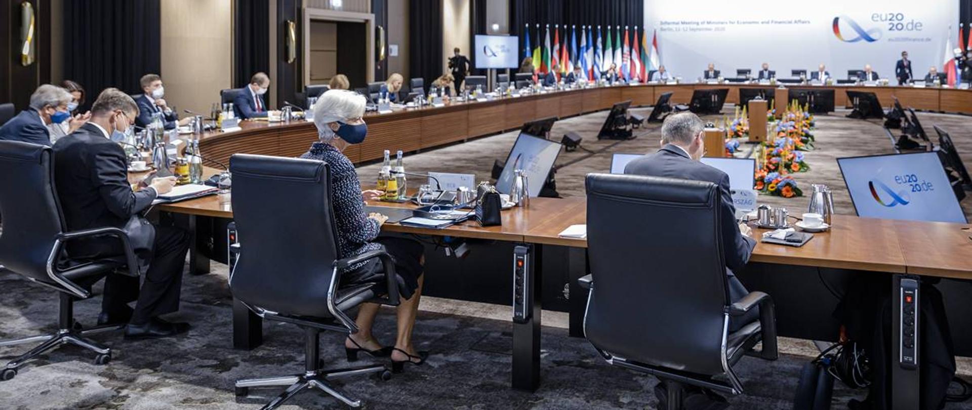 Spotkanie ECOFIN, uczestniczy siedzą wokół stołu, w tle flagi państw UE