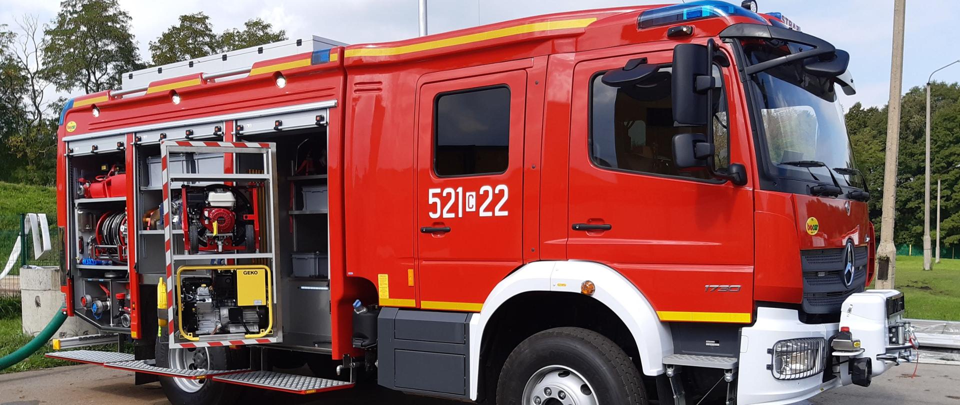 Na zdjęciu widoczny jest pojazd ratowniczo-gaśniczy ustawiony bokiem z otwartymi skrytkami.