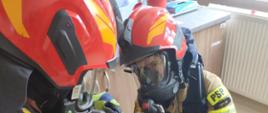 Na zdjęciu widoczni strażacy w ubraniach specjalnych koloru granatowego w hełmach strażackich oraz udzielający kwalifikowanej pierwszej pomocy poszkodowanemu podczas ćwiczeń na oddziale geriatrycznym w szpitalu specjalistycznym w Gorlicach.