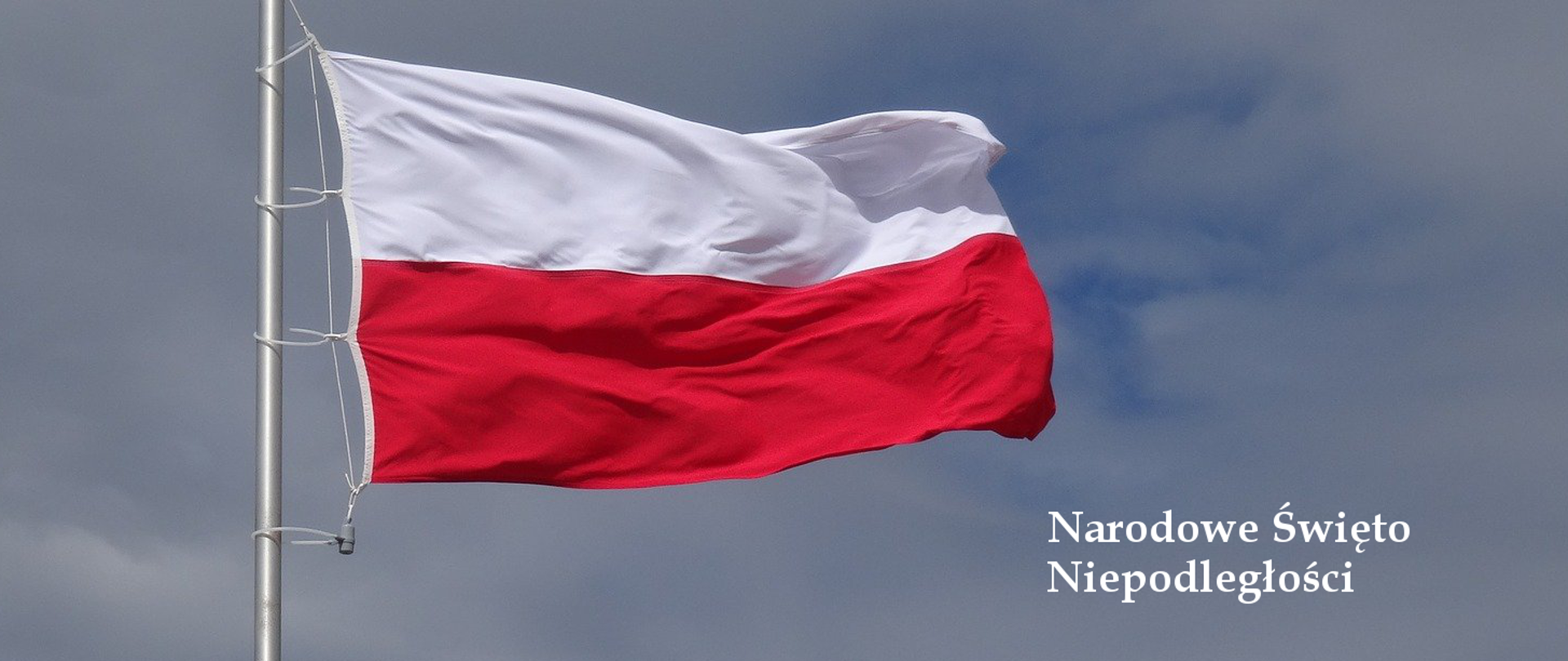 Flaga Rzeczypospolitej Polskiej na tle nieba. Po prawej stronie napis "Narodowe Święto Niepodległości"