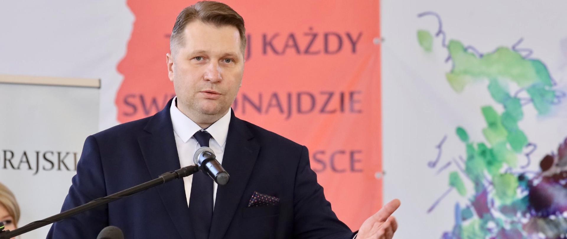 Dzień Edukacji Narodowej i otwarcie odnowionej hali sportowej przy Zespole Szkół Budowlanych i Ogólnokształcących w Biłgoraju z udziałem ministra Przemysława Czarnka, minister Przemysław Czarnek przemawia, stoi przy mównicy.