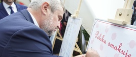 Minister Ardanowski podczas składania pamiątkowego podpisu