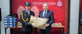 Na zdjęciu widoczny Prezydent Miasta Ostrowca Św. oraz Komendant Powiatowy Państwowej Straży Pożarnej w Ostrowcu Św. podczas przekazania przez Prezydentan 8 kompletów ubrań służbowych.