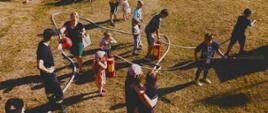 Widok z góry: dzieci podają wodę z hydronetek i osoby zgromadzone na pikniku