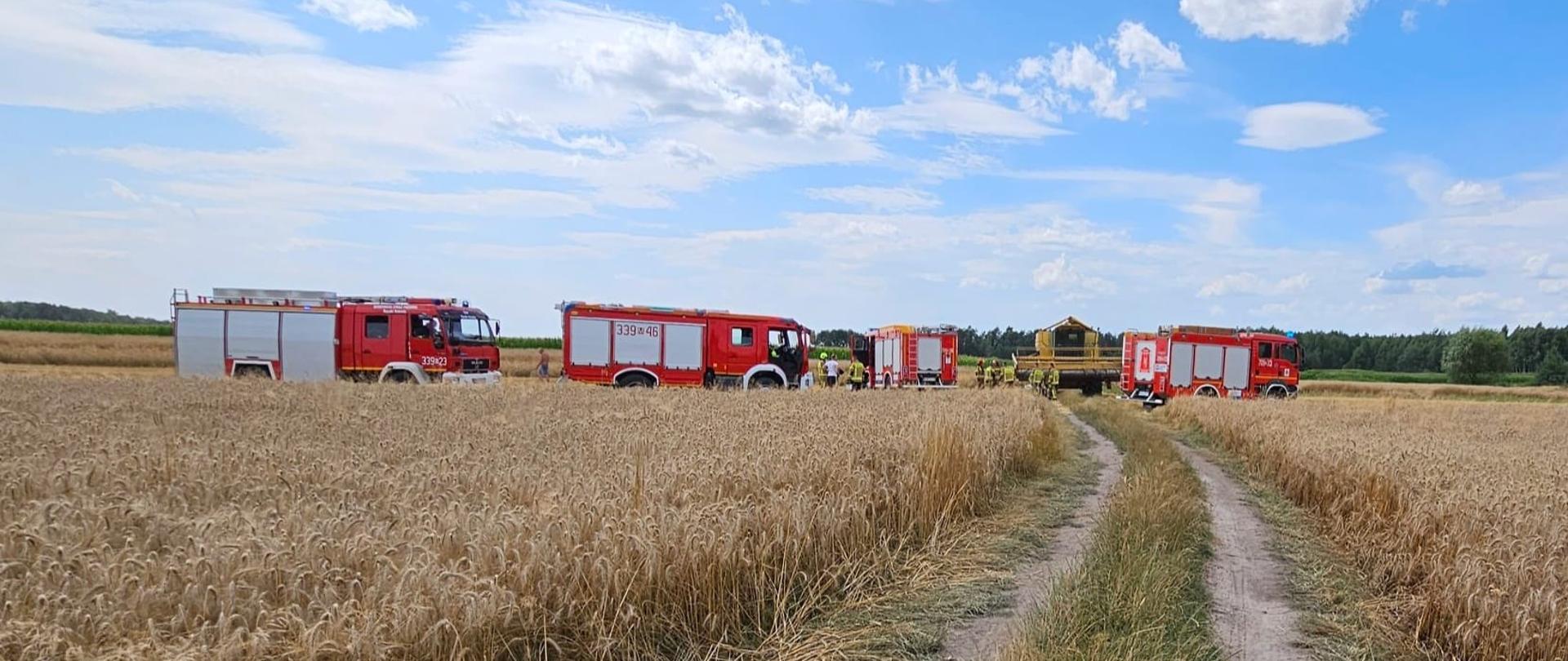 Wozy strażackie oraz kombajn na polach