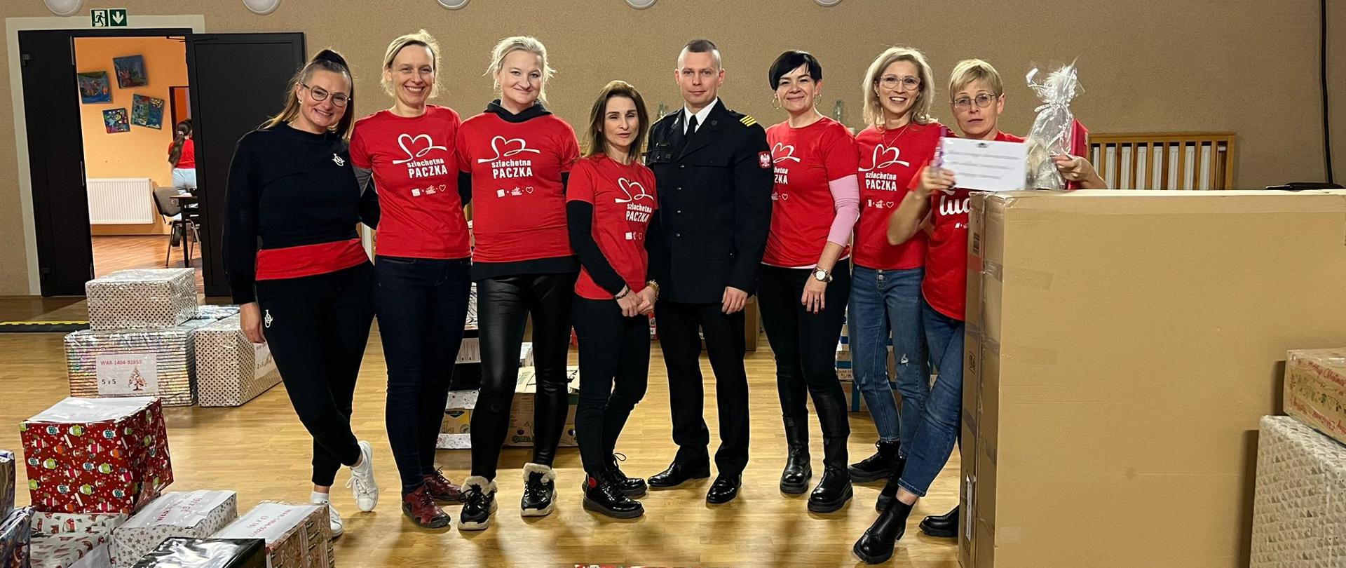 Zdjęcie przedstawia grupę wolontariuszy szlachetnej paczki oraz funkcjonariusza lidzbarskiej straży.