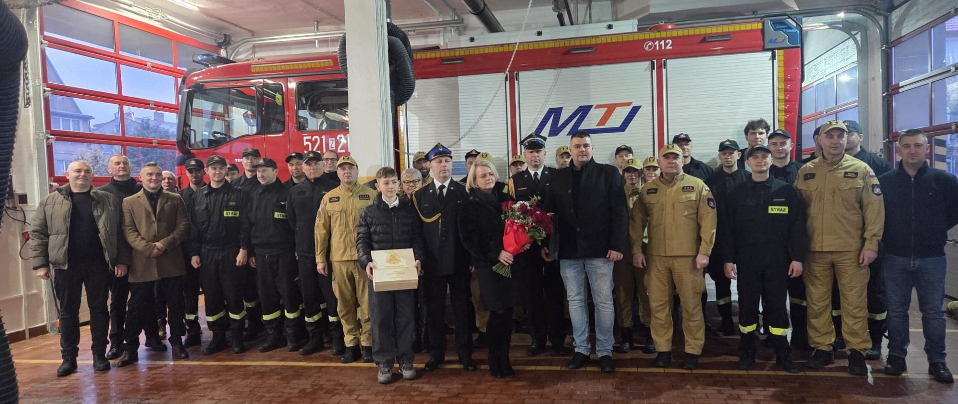 Wspólne zdjęcie funkcjonariuszy PSP i zaproszonych gości podczas uroczystego pożegnania strażaka w Jednostce Ratowniczo-Gaśniczej