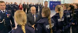 na pierwszym planie widać tył pleców policjantek, gratuluje im uśmiechnięty mężczyzna