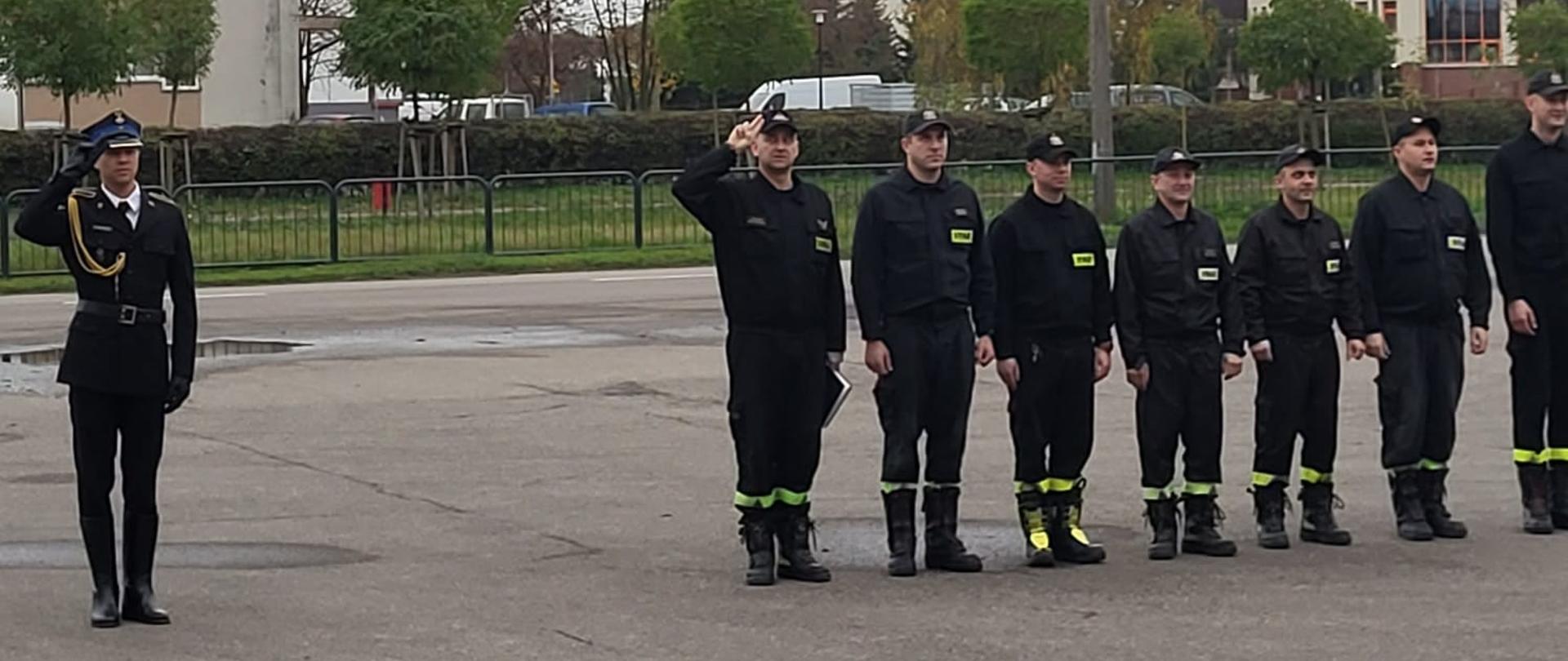 Strażacy stoją na baczność na uroczystej zbiórce