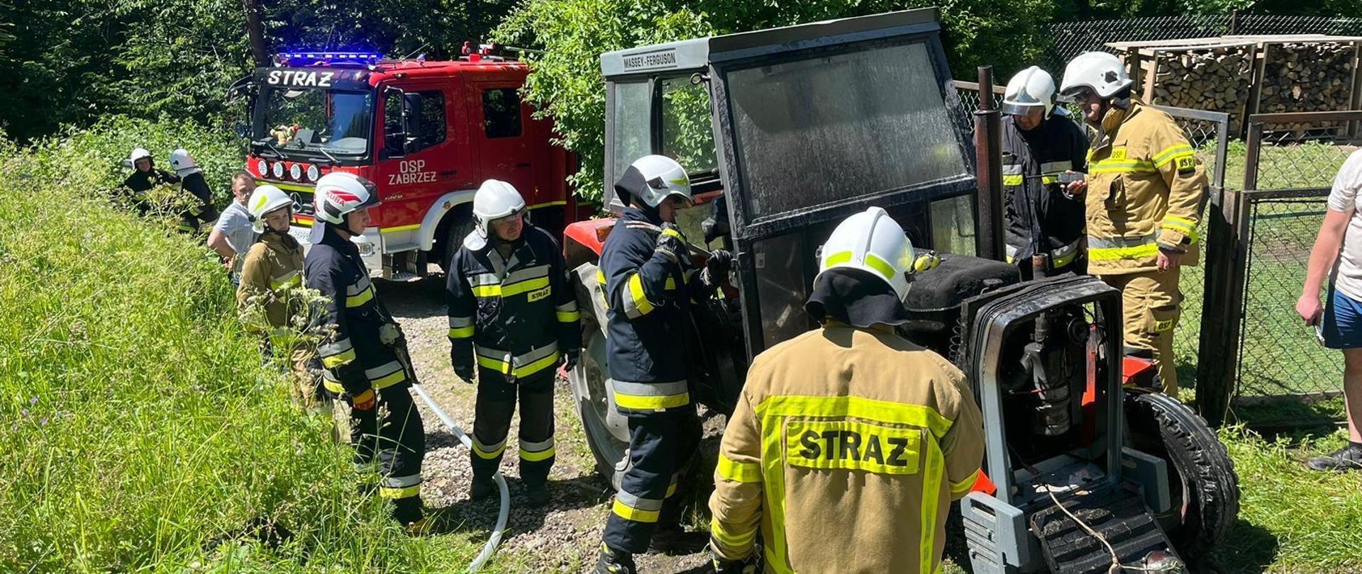 Strażacy obok spalonego traktora