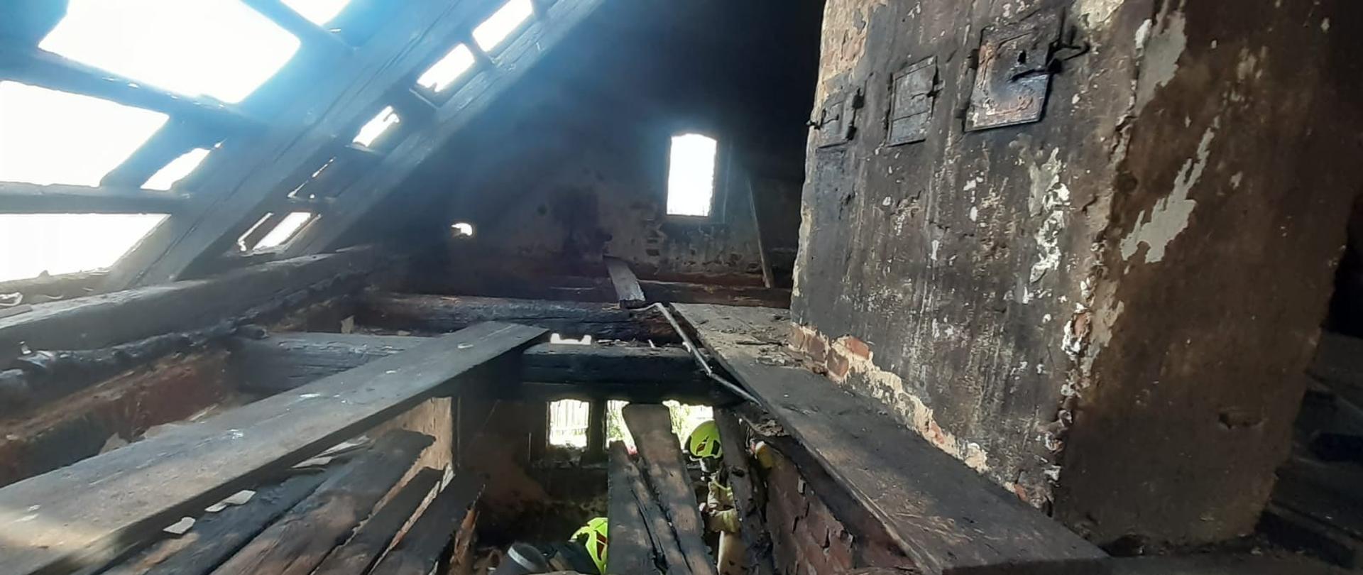 Widok na poddasze domu po ugaszeniu ognia. Widać okopcone ściany i deski