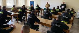 Zdjęcie przedstawia strażaków w trakcie egzaminu, w tle widoczna komisja egzaminacyjna,