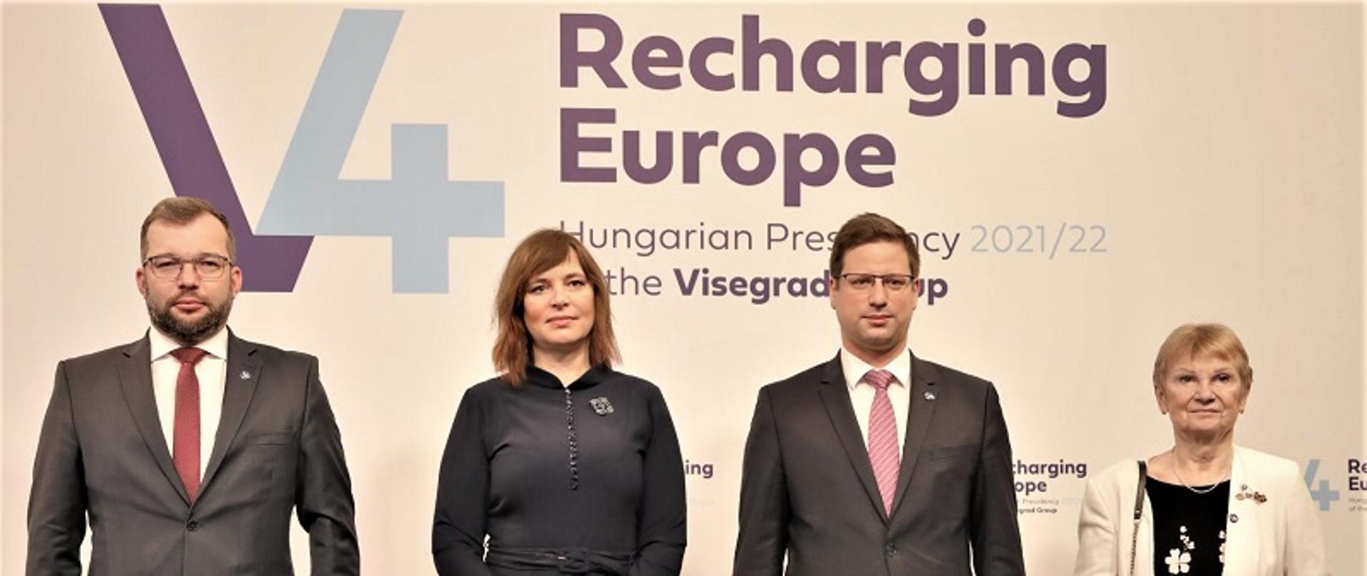 Cztery osoby stoją na ściance z napisem V4 Recharging Europe. 