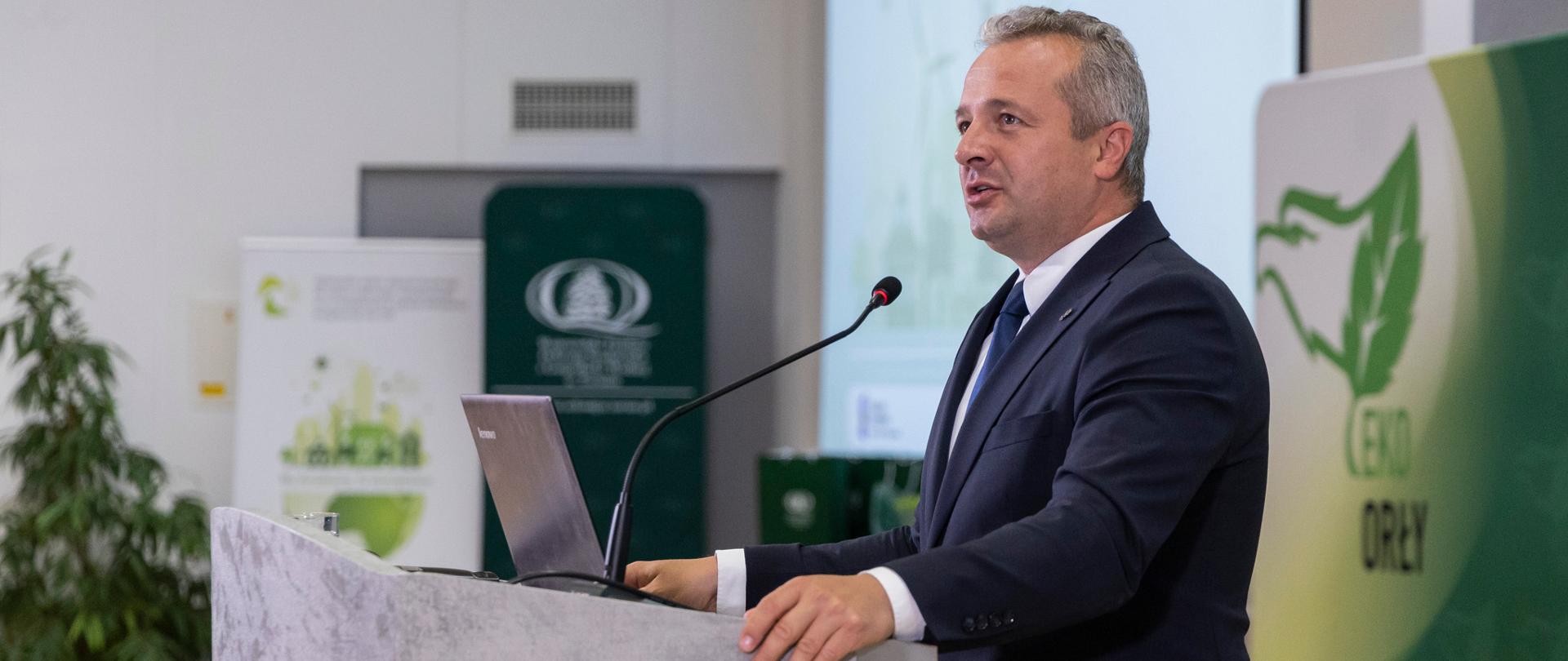 Jeden mężczyzna stojący przed mównicą i wypowiadający się 