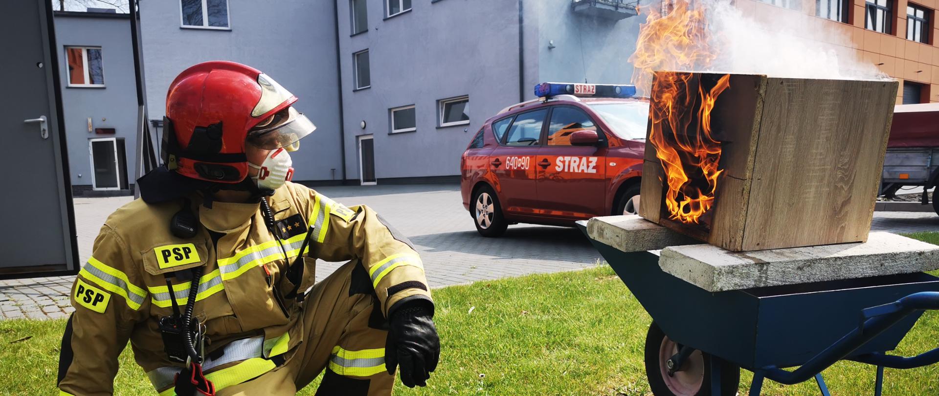Palący się domek ogniowy, strażak po lewej stronie.