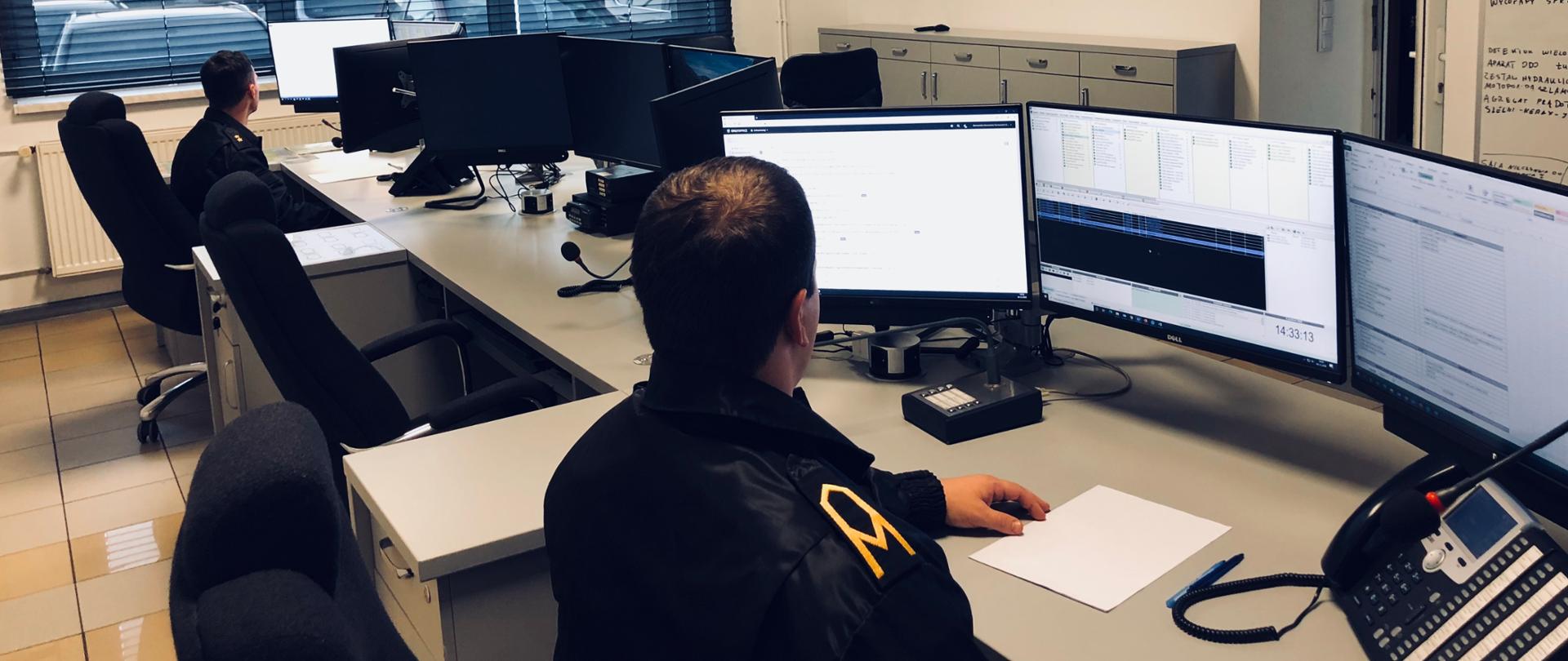 Stanowisko Kierowania Komendanta Powiatowego w Tarnowskich Górach. Zdjęcie przedstawia pracę dwóch funkcjonariuszy podczas pełnienia służby. 