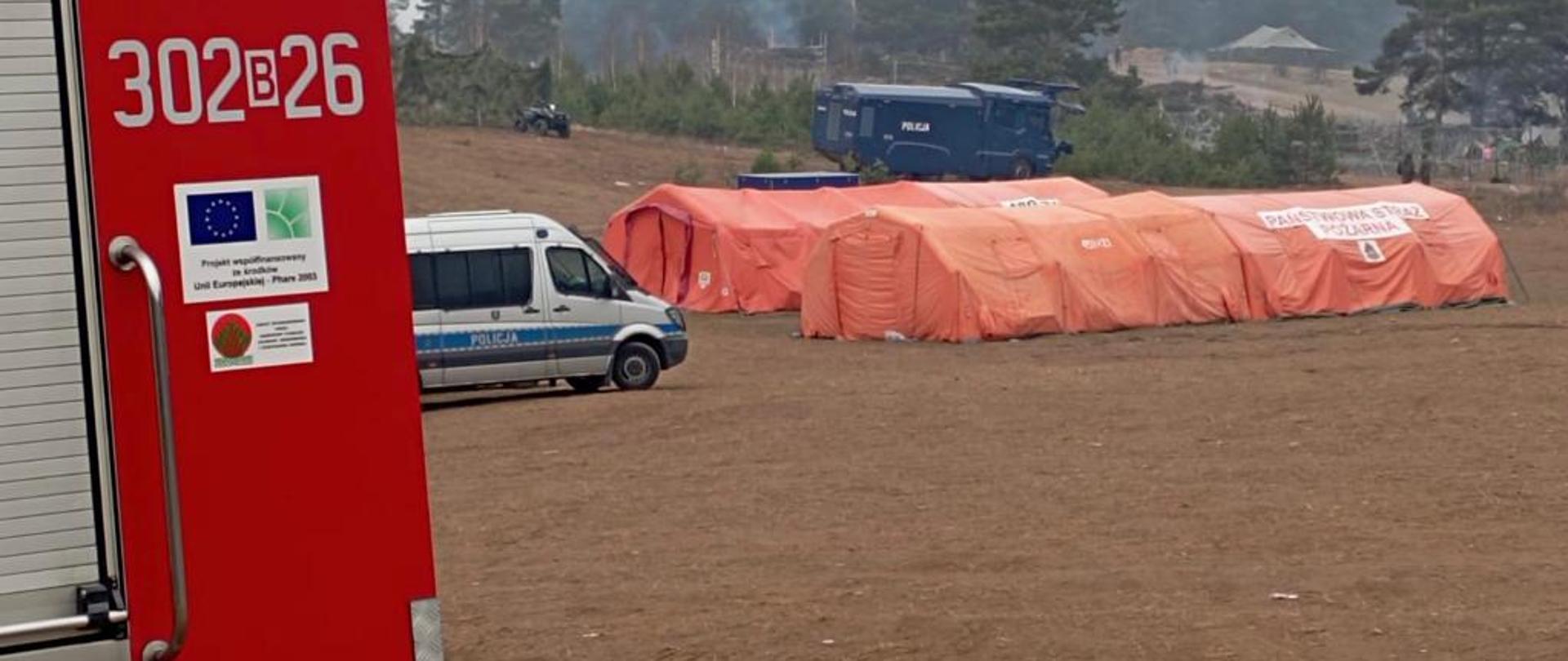 widok namiotów, auta policji i straży
