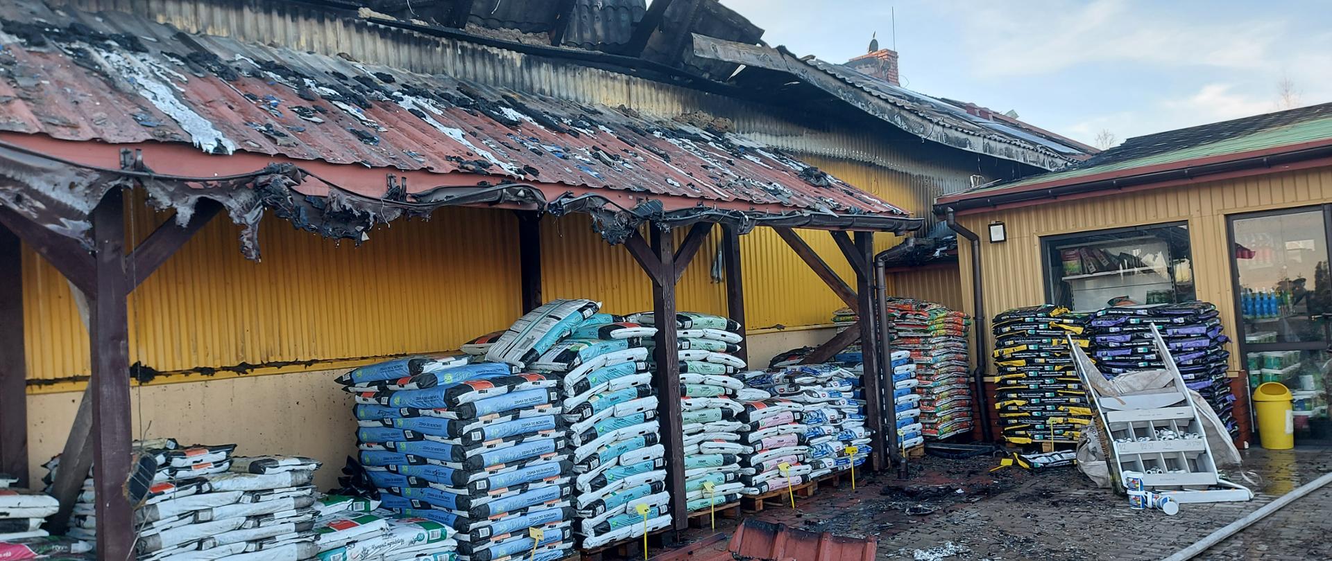 Zdjęcie przedstawia spalony budynek hurtowni ogrodniczej