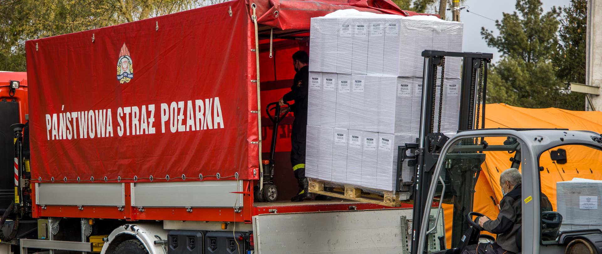Na zdjęciu widoczny samochód kwatermistrzowski PSP podczas załadunku palet z maseczkami dla mieszkańców województwa opolskiego. 