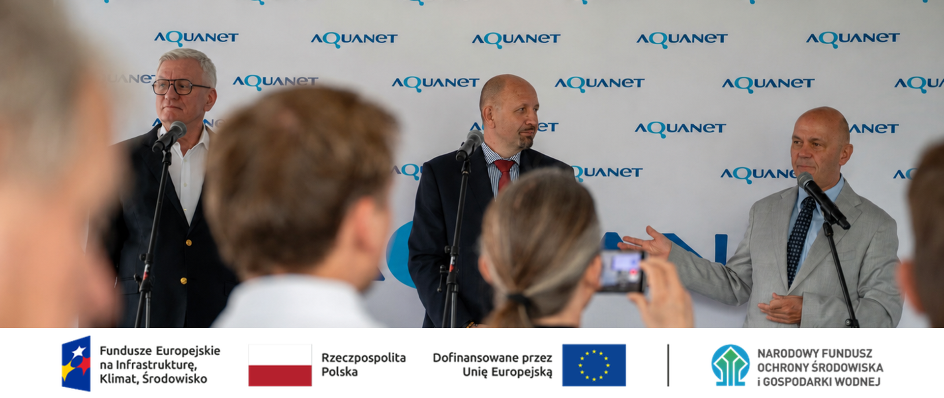 Zdjęcie grupowe. W stopce grafiki ciąg logotypów: Fundusze Europejskie na Infrastrukturę, Klimat, Środowisko, flaga Rzeczypospolita Polska, flaga UE i Dofinansowane przez UE, NFOŚiGW.