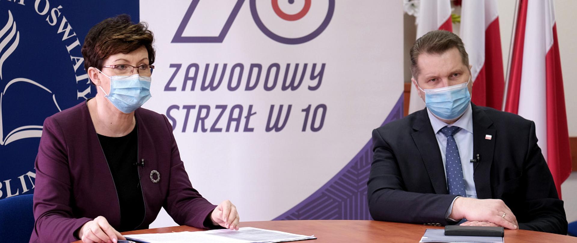 Minister Czarnek i kurator Misiuk siedzą za stołem, za nimi napis Kuratorium Oświaty w Lublinie.