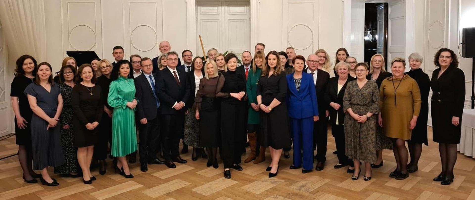 Uczestnicy Ogólnopolskiej Narady Najwyższego Kierownictwa IJHARS w dniach od 15 do 17 kwietnia 2026r. Pracownicy stoją w sali Zespołu Pałacowo – Parkowego w Koszęcinie. 