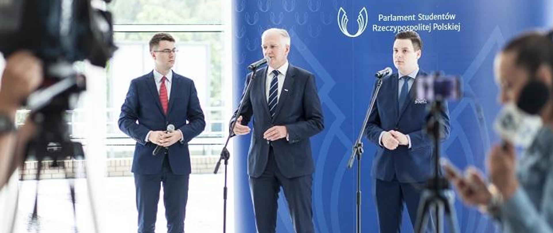 Na tle ściany z napisem Parlament Studentów RP stoją ministrowie Gowin i Muller