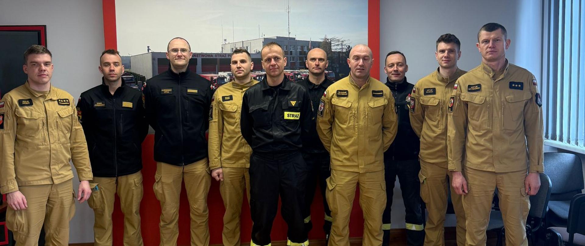 Strażacy stoją w szeregu w pomieszczeniu.