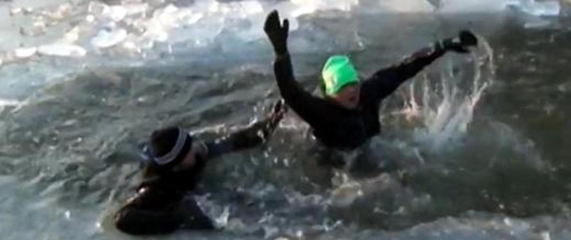 Zdjęcie przedstawia ludzi, pod którymi zarwał się lód i potrzebują pomocy