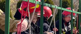 Zawodnicy przebrani w umundurowanie strażackie wiążą węzły ratownicze 