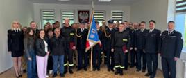 Zdjęcie grupowe na tle godła oraz z sztanderem KM PSP w Koszalinie