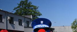 Maskotka policji sznupek pozuje na tle komendy