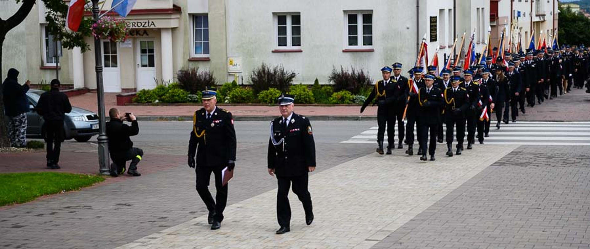 Zdjęcie obrazuje uformowany pododdział strażaków, który jest prowadzony przez Komendanta Powiatowego PSP w Skarżysku-Kamiennej st. bryg. Marcina Machowskiego oraz Marszałka Województwa Świętokrzyskiego Andrzeja Bętkowskiego.. W pododdziale znajdują się strażacy Państwowej Straży Pożarnej oraz druhowie Ochotniczych Straży Pożarnych z terenu powiatu skarżyskiego. 