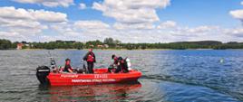 trzech strażaków i dwóch płetwonurków w czerwonej łodzi na jeziorze