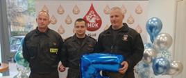 Funkcjonarjusze KP PSP w Grodzisku Mazowieckim po oddaniu krwii pozują na ściance Klubu „Jednostka HDK” przy Komendzie Wojewódzkiej Państwowej Straży Pożarnej w Warszawie.