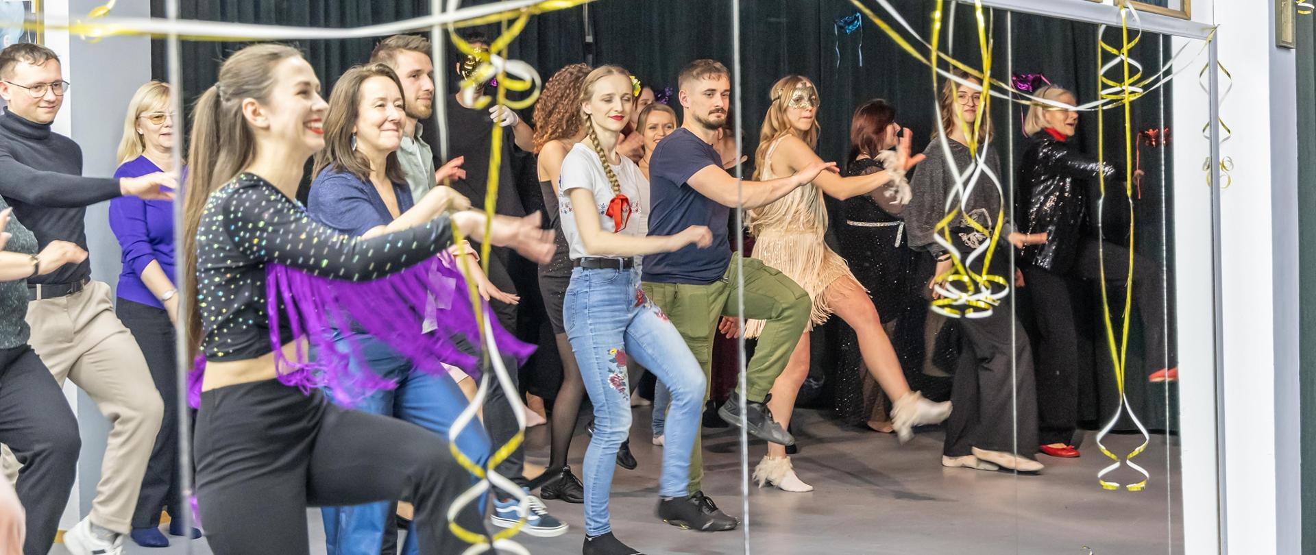 Zajęcie przedstawia osoby tańczące na sali tanecznej w Studium. Tańczą naprzeciwko dużych luster a zdjęcie przedstawia ich odbicia lustrzane. 