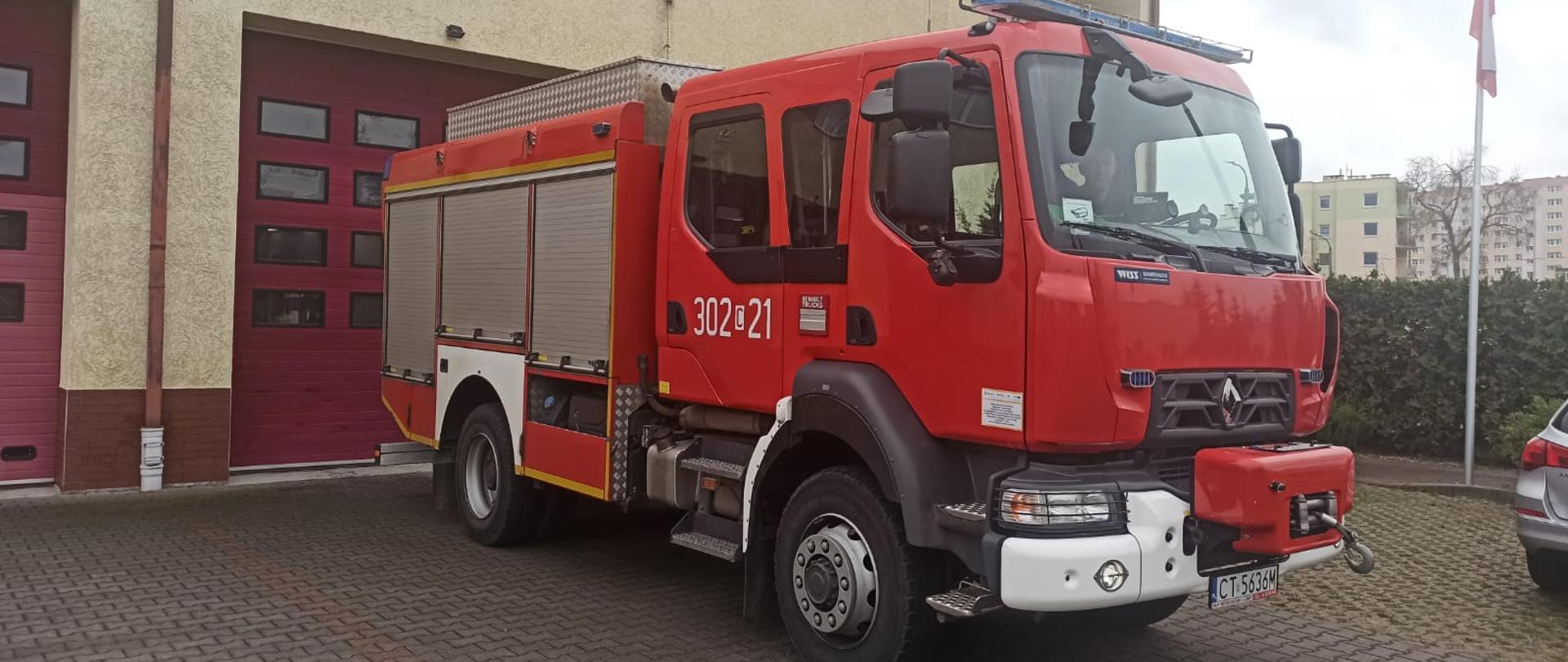 Samochód strażacki ciężarowy ratowniczo-gaśniczy Jednostki Ratowniczo-Gaśniczej nr 2 w Bydgoszczy, podwozie marki Renault, w tle budynek jednostki.