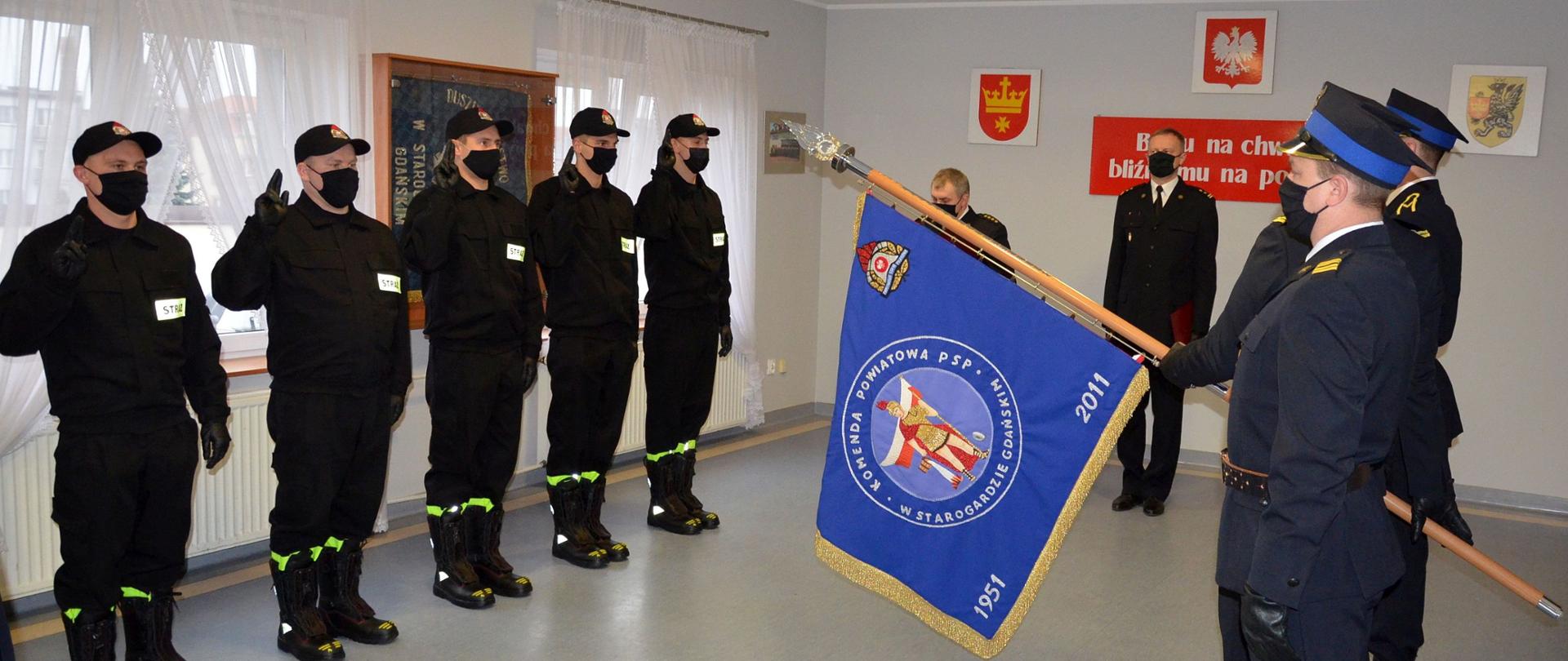 Zdjęcie przedstawia moment składania przysięgi przez nowo przyjętych do pracy strażaków. Widać poczet sztandarowy i kierownictwo komendy.